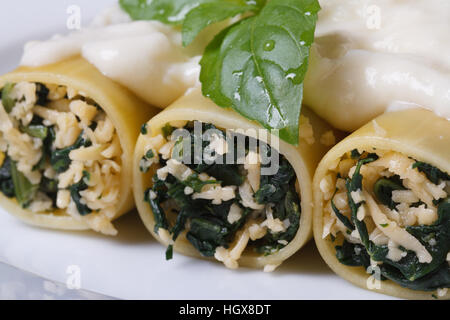 Italienische Pasta Cannelloni gefüllt mit Spinat und Käse mit Bechamel-Sauce und Basilikum-Makro Stockfoto