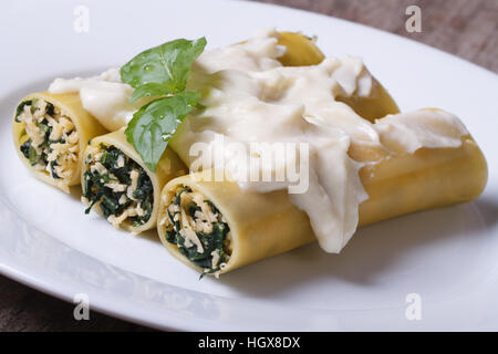 Italienische Pasta Cannelloni gefüllt mit Spinat und Käse mit Bechamel-Sauce und Basilikum in der Nähe, horizontal Stockfoto