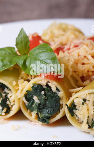 Italienische Pasta Cannelloni gefüllt mit Spinat und Käse mit Tomaten-Sauce und Basilikum Makro vertikalen Stockfoto