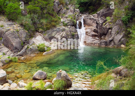 Ein kleiner Wasserfall und grüne Lagune, die versteckt in den Bergen. Arado-Fluss, Nationalpark Peneda-Geres, Portugal. Stockfoto