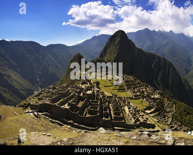 Inka-Stadt Machu Picchu im Nachmittag starke und harte Sonnenlicht. Wayna Pichu und blauer Himmel mit Wolken im Hintergrund Stockfoto