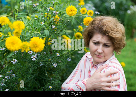 Frau, die leiden unter Kopfschmerzen, die allergisch auf Blumen Stockfoto