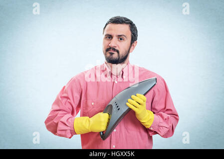 Lächelnder junger Mann mit Handstaubsauger Stockfoto