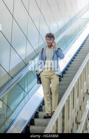 Geschäftsmann am Handy auf einer Rolltreppe sprechen Stockfoto