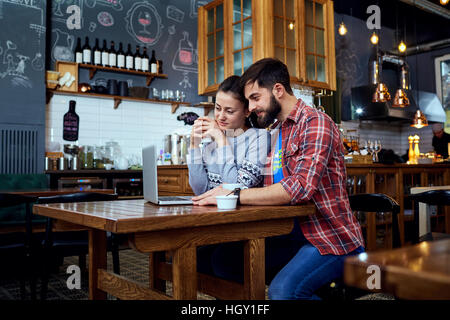 Junges Paar lesen, mit Blick auf einen Laptop im café Stockfoto