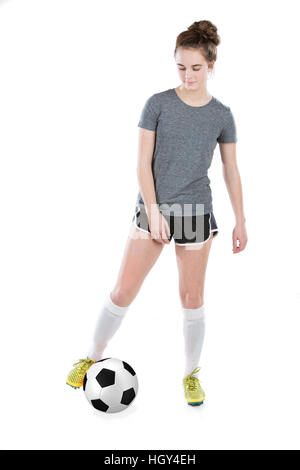 Teenager-Mädchen tragen Fußball-Stollen und shin Guards spielen mit einem Fußball zwischen ihren Füßen.  Konzept für Schulsport oder Teen Sport. Stockfoto