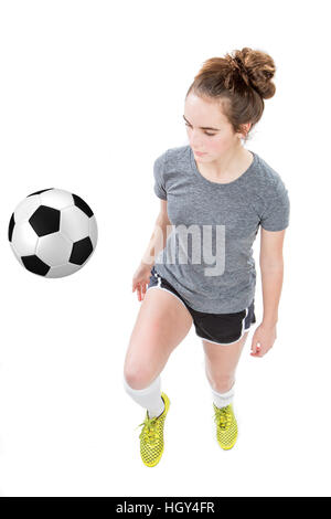 Teenager-Mädchen tragen Fußball-Stollen und shin Guards dribbling einen Fußball mit ihrem Knie. Konzept für Schule Sport oder Teenager-Fußball-Liga. Stockfoto