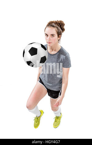 Teenager-Mädchen tragen Fußball-Stollen und shin Guards dribbling einen Fußball mit ihrem Knie. Konzept für Schule Sport oder Teenager-Fußball-Liga. Stockfoto