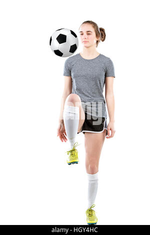 Teenager-Mädchen tragen Fußball-Stollen und shin Guards dribbling einen Fußball mit ihrem Knie. Konzept für Schule Sport oder Teenager-Fußball-Liga. Stockfoto