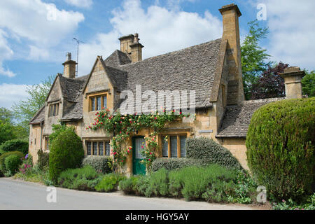 Cotswold Landhaus aus Stein mit roten und gelben Rosen. Stanton, Cotswolds, Gloucestershire, England Stockfoto