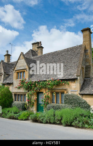 Cotswold Landhaus aus Stein mit roten und gelben Rosen. Stanton, Cotswolds, Gloucestershire, England Stockfoto