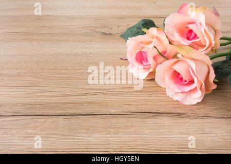 Drei Rosa Rosen auf braunem Holz Hintergrund Stockfoto