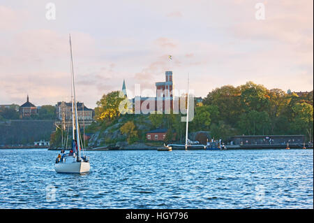 Die einsame Yacht segelt in der Saltsjon-Bucht mit der Insel Kastellholmen und dem Kastellet auf dem Hintergrund Stockfoto