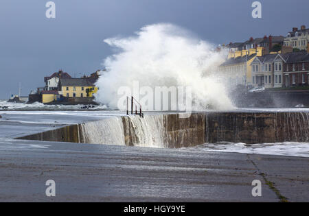 Ein Wintersturm Buffets eine Hafenmauer senden Wellen Schaum und Gischt in die Luft und Vorhänge Wasser cascading ins Meer Stockfoto