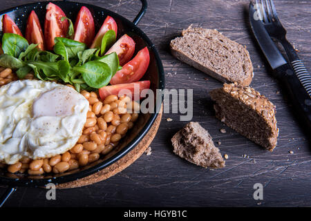 Frühstück mit Bohnen, Tomaten, Eiern und Brot. Stockfoto