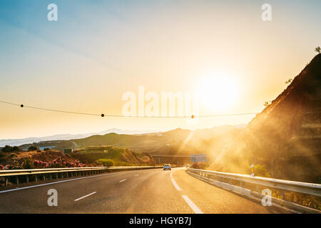 Bewegung von Fahrzeugen auf Autobahn, Autobahn e-15 in der Nähe von Malaga in Spanien. Sonnenuntergang Stockfoto