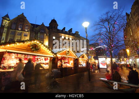 Festliche Shopper durchsuchen waren in niedlichen Holzhütten auf dem Weihnachtsmarkt am Fargate Sheffield Stadtzentrum Yorkshire, England Stockfoto