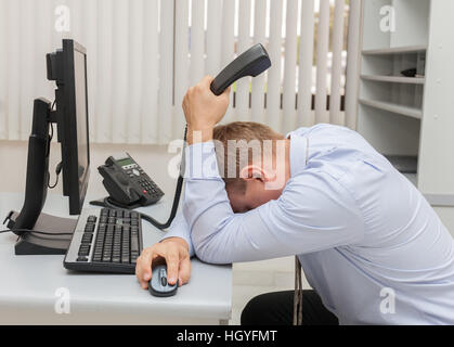 Junger Geschäftsmann mit Problemen und Stress im Büro vor dem Computer sitzen Stockfoto