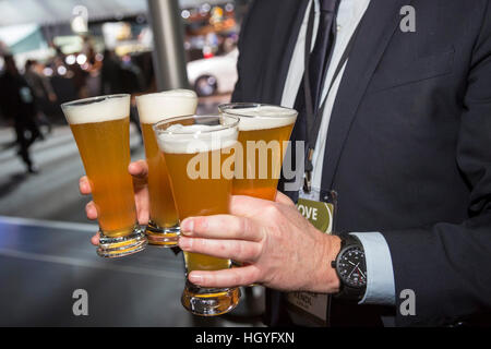 Detroit, Michigan - ein Mann trägt vier Gläser Bier während der Teilnahme an der North American International Auto Show. Stockfoto