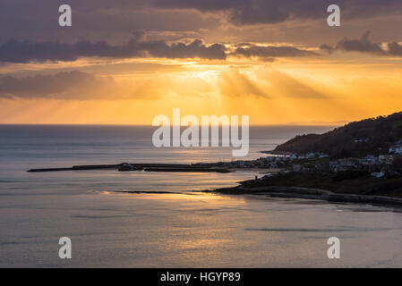 Lyme Regis, Dorset, UK.   13. Januar 2017.  Großbritannien Wetter.  Dramatische Sonnenstrahlen über den Badeort Lyme Regis während des Sonnenuntergangs an der Küste von Dorset Jurassic aus betrachtet die Klippen von Charmouth.  Bild: Graham Hunt/Alamy Live-Nachrichten. Stockfoto