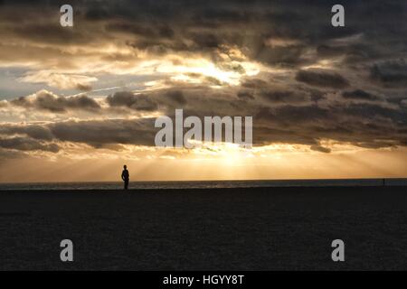 West Bay, Dorset, UK. 14. Januar 2017. Großbritannien Wetter.  Eine Strand-Walker ist von einem herrlichen Sonnenuntergang nach einem kalten Tag auf der Küste von Dorset Silhouette. Bildnachweis: Tom Corban/Alamy Live-Nachrichten Stockfoto