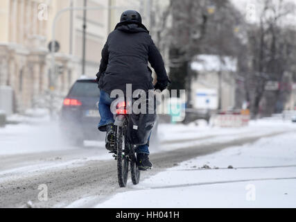 München, Deutschland. 15. Januar 2017. Ein Radfahrer fährt entlang einer Straße im Schnee in München, Deutschland, 15. Januar 2017 bedeckt. In der Nacht in München sind mehrere Zentimeter Neuschnee gefallen. Foto: Tobias Hase/Dpa/Alamy Live News Stockfoto