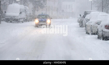 München, Deutschland. 15. Januar 2017. Ein Auto fährt entlang einer Straße im Schnee in München, Deutschland, 15. Januar 2017 bedeckt. Foto: Stefan Puchner/Dpa/Alamy Live News Stockfoto