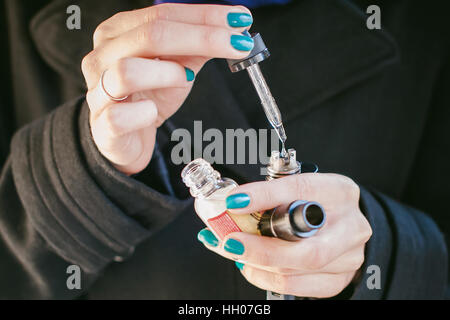 Portrait von junge schöne Frau mit weißem Haar, in einen schwarzen Mantel, einen Rock und einen schwarzen Hut, eine elektronische Zigarette rauchen läuft Vape Saft Elektron Stockfoto