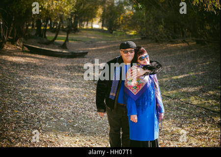 Erwachsene Paare, die im Herbst Park. Mann und Frau zu Fuß im Freien im Herbst letzten Tage, Mann mit einem Schnurrbart tragen Sonnenbrillen Stockfoto