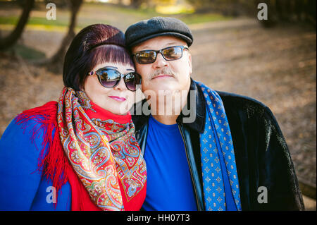 Erwachsene Paare, die im Herbst Park. Mann und Frau zu Fuß im Freien im Herbst letzten Tage, Mann mit einem Schnurrbart tragen Sonnenbrillen Stockfoto