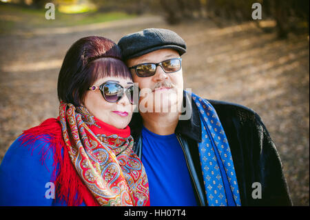 Erwachsene Paare, die im Herbst Park. Mann und Frau zu Fuß im Freien im Herbst letzten Tage, Mann mit einem Schnurrbart tragen Sonnenbrillen Stockfoto