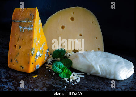 Frische Stücke Käse (Mozzarella, Roquefort, Maasdam) auf den steinernen Tisch Stockfoto