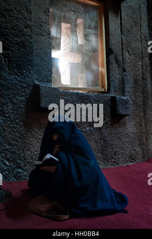 Lalibela, Amhara Region, Äthiopien. Eine Frau betet im Inneren der Kirche Bet Medhane Alem. Die Kirchen von Lalibela zu bewundern, die man nicht sehen upwa Stockfoto