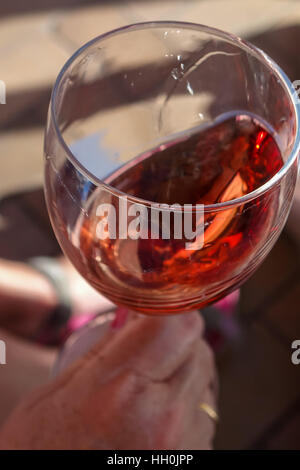 Glas Rose Wein verwirbelt, mit Hand in Schuss Stockfoto