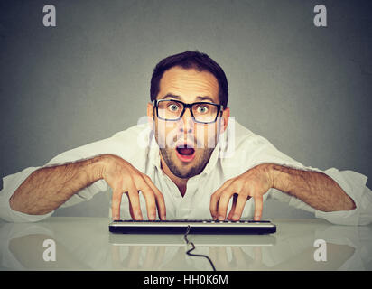 Verrückte nerdy lustig aussehenden Mann in Gläsern Tippen auf der Tastatur Stockfoto