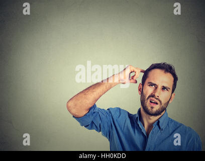 Mann Kopf kratzen, etwas tief nachzudenken, nachschlagen, isoliert auf grauem Hintergrund. Menschlichen Gesichtsausdruck, Emotionen, Stockfoto