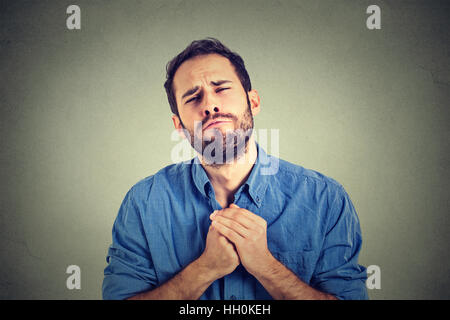 verzweifelter jungen Mann zeigt gefalteten Händen ziemlich bitte mit Zucker obendrauf isoliert auf grauem Hintergrund. Menschliche Emotionen Gesichts Stockfoto