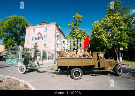 Gomel, Weißrussland - 9. Mai 2016: Russische sowjetische Militär-LKW ZIS-5V mit Männern In Uniform der Soldaten an Bord, Waffe, rote Fahne des 2. Weltkrieges, Abschleppen 57 Mm ZiS-2 Stockfoto