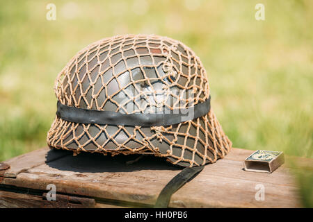 Schließen Sie den Metall Helm des Infanterie-Soldat der Wehrmacht, Streitkräfte der Nazi-Deutschland während des zweiten Weltkriegs, liegend auf der alten Holzkiste auf dem Grün Gr Stockfoto