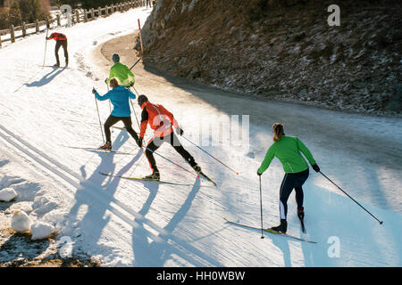 Junges Team Ski Crosstraining Land auf einer kurvenreichen Bergstraße in bunten Ski-Kleidung Stockfoto