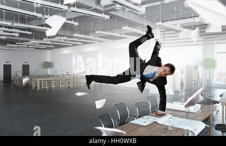 Fröhliche Jungunternehmer tanzen in seinem Büro. Mixed-media Stockfoto