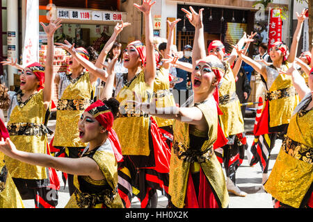 Japanische Yosakoi Dance Festival. Weibliche Mannschaft, die historische Geschichte Tanz in der Einkaufspassage. In der traditionellen Yukata bekleidet, gold gefärbt. Stockfoto