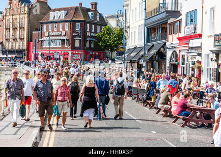 Massen von Menschen zu Fuß entlang der Strandpromenade Straße in Ramsgate Stadt genießen der Bank Holiday Hitzewelle im August, während andere an den Tischen sitzen, trinken. Stockfoto