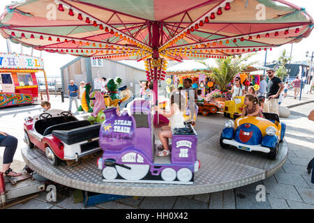 England, Ramsgate. Kinder freuen sich über kleine Auto und Zug Karussell am Meer im Sommer Hitzewelle. Stockfoto