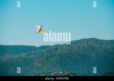 Motorisierte Hang Glider fliegen über Berg Hügel auf blauem Himmelshintergrund der klaren sonnigen. Stockfoto