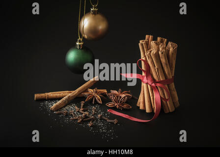 Zimt-Sticks, Sternanis und Nelken mit zwei Weihnachtskugeln Stockfoto