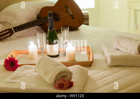 Romantik im Bett mit Champagner und Gitarre Stockfoto