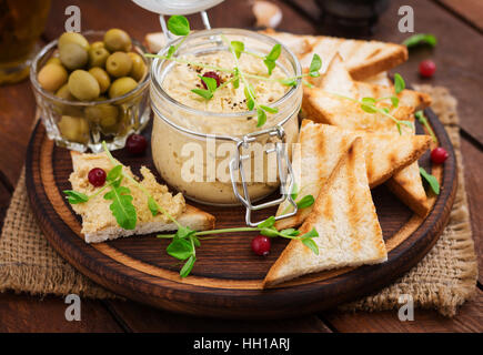 Pastete Huhn - Rillette, Toast, Oliven und Kräutern auf einem Holzbrett Stockfoto