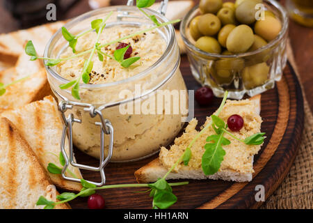 Pastete Huhn - Rillette, Toast, Oliven und Kräutern auf einem Holzbrett Stockfoto
