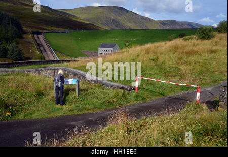 Frau Walker Blick auf der touristischen Infotafel am Loch Turm-Staudamm im Glen Revolver in den schottischen Highlands Schottland, Großbritannien. Stockfoto